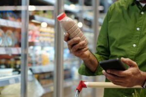 woman grocery shops, looks at drink label