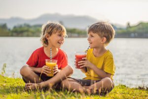 girl and boy enjoy a beverage flavor as they drink from straws in a shared bottle smiling 