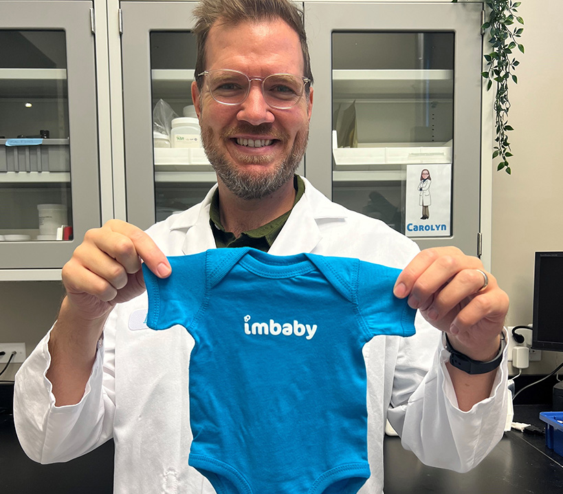 Scientist in lab holding Imbibe onesie